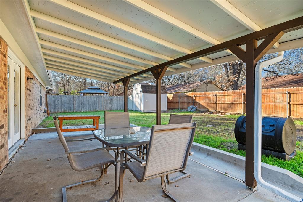 921 Red Oak Street Azle, TX 76020 - Photo 15 of 16 Fenced backyard featuring outdoor dining area, a patio, and a shed
