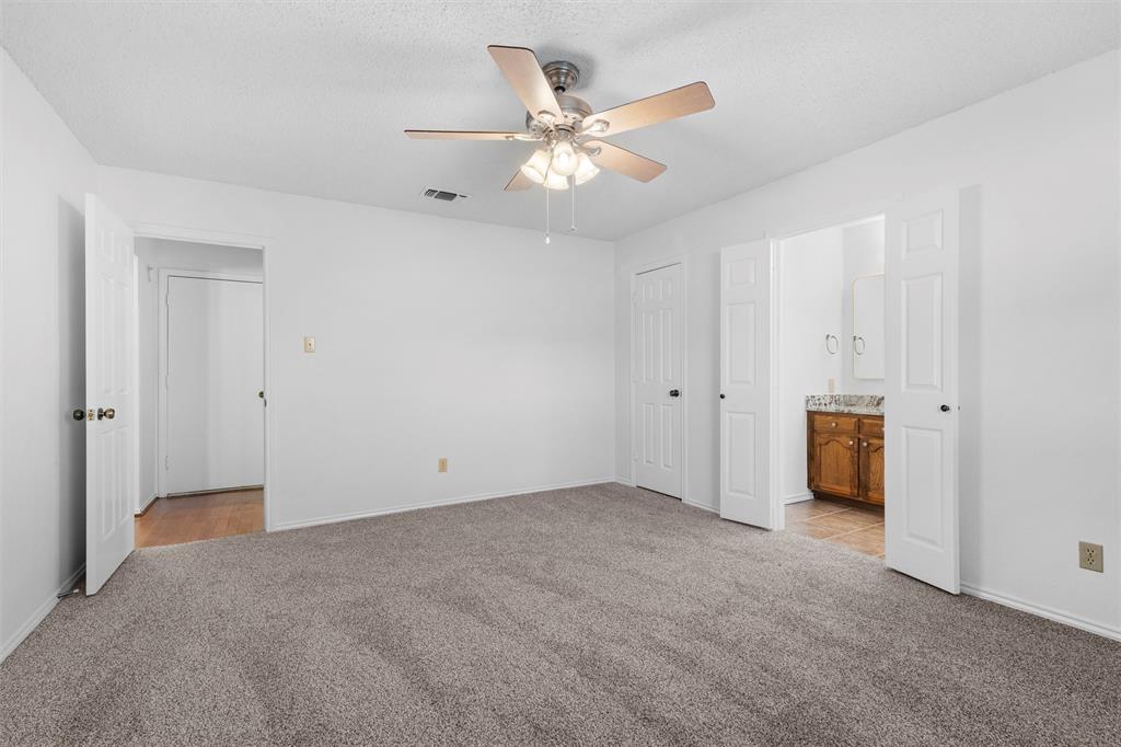 921 Red Oak Street Azle, TX 76020 - Photo 5 of 16 Primary bedroom featuring light colored carpet, ensuite bathroom, ceiling fan, and a closet