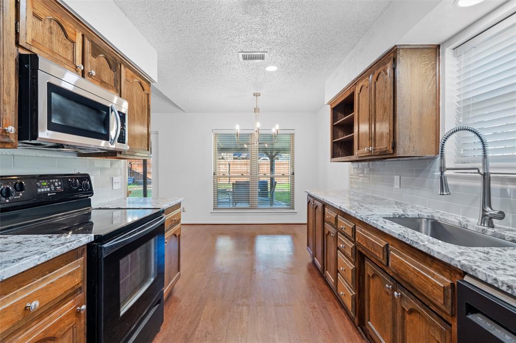 921 Red Oak Street Azle, TX 76020 - Photo 7 of 16 Kitchen with black appliances, open shelves, light stone countertops, tasteful backsplash, and a textured ceiling