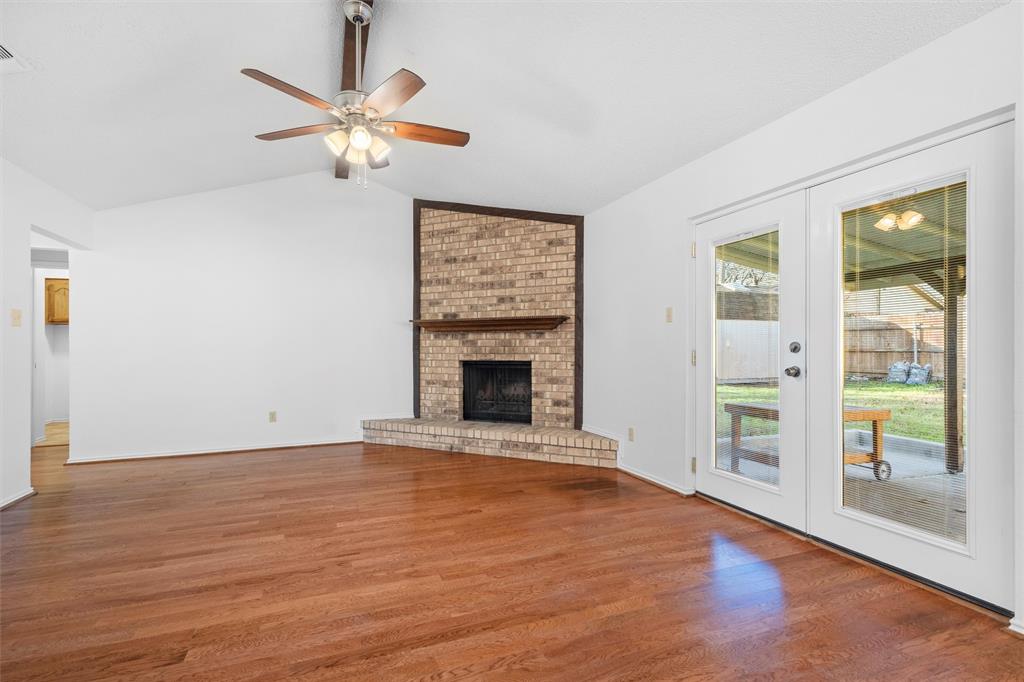 921 Red Oak Street Azle, TX 76020 - Photo 9 of 16 Living room with wood finished floors, a brick fireplace, ceiling fan, french doors, and beam ceiling