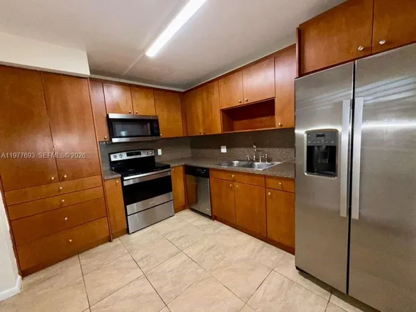 a kitchen with stainless steel appliances kitchen island granite countertop a refrigerator stove and sink