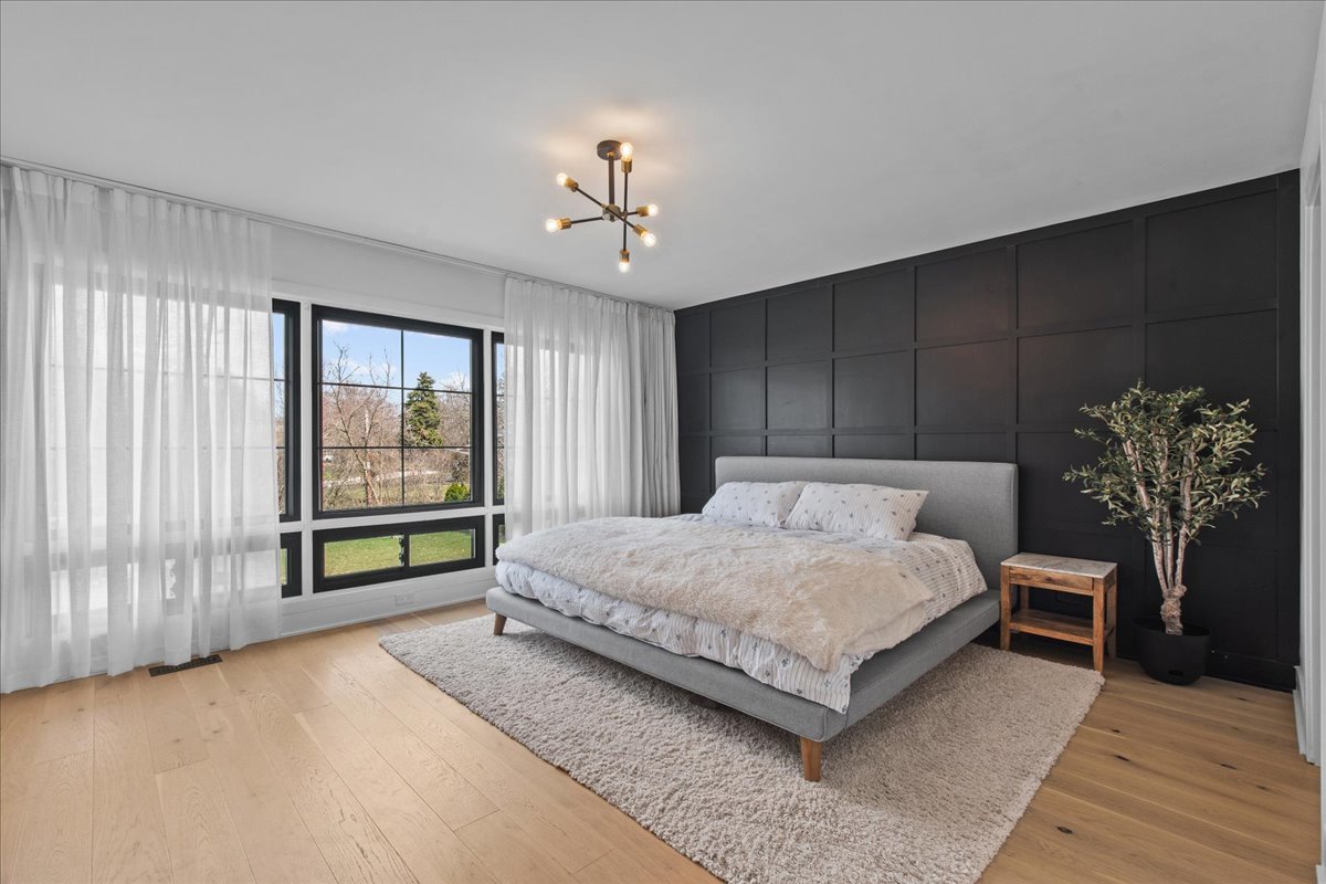 1975 Valley View Road Northfield, IL 60093 - Photo 24 of 45 a spacious bedroom with a bed and a chandelier