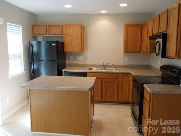 a kitchen with stainless steel appliances granite countertop a refrigerator a sink a stove and a refrigerator