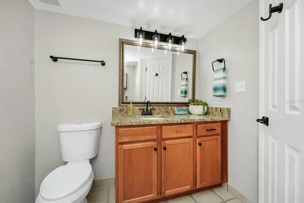 a bathroom with a granite countertop toilet sink and mirror