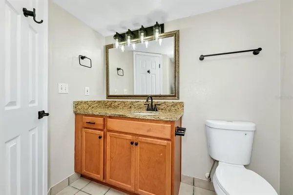 a bathroom with a granite countertop toilet sink and mirror