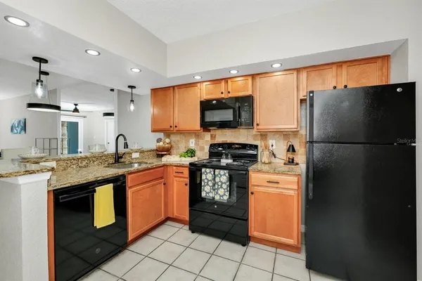 a kitchen with stainless steel appliances granite countertop a refrigerator a stove a sink and a microwave