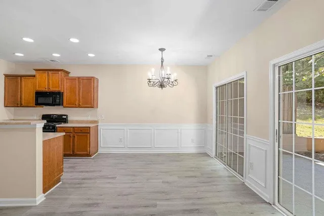 an empty room with wooden floor and stainless steel appliances