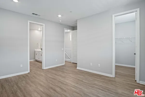 an empty room with wooden floor & windows and bathroom