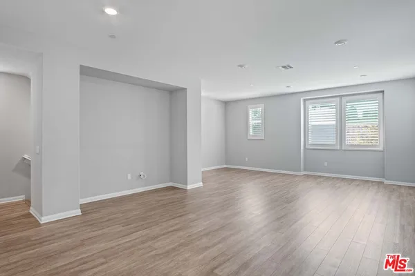 a view of an empty room with wooden floor and windows