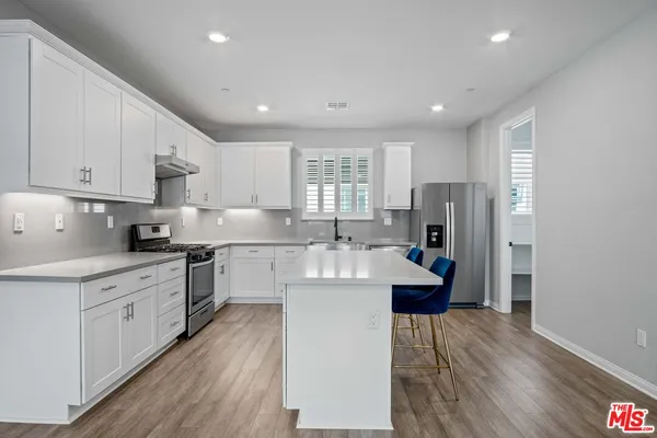 a large kitchen with stainless steel appliances lots of counter space and wooden floor