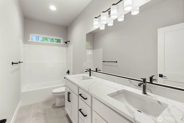 a bathroom with a double vanity sink a toilet and a mirror