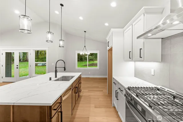 a large kitchen with kitchen island a large window a sink a counter space and stainless steel appliances