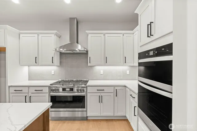 a kitchen with stainless steel appliances white cabinets and a stove top oven
