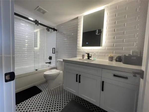 a bathroom with a sink toilet a mirror and shower