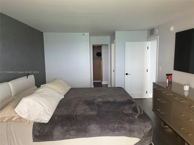 a bedroom with a bed and a flat tv screen on dresser