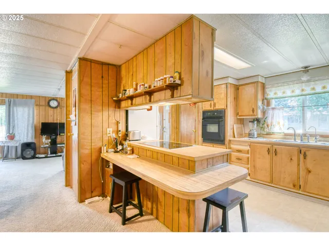 a view of a kitchen with kitchen island granite countertop a sink cabinets and living room view