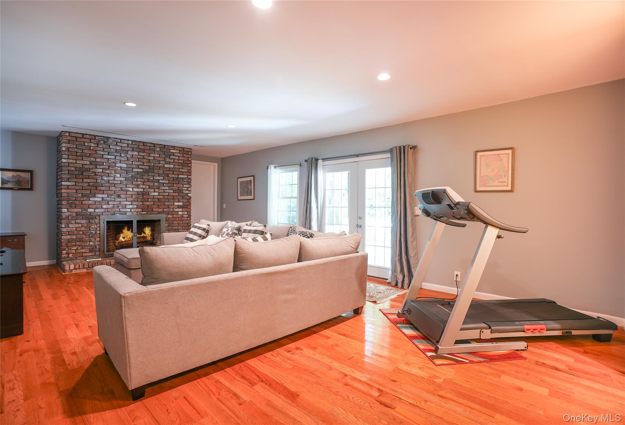 22 Peters Lane Pound Ridge, NY 10576 - Photo 28 of 43 Living area featuring wood-finish flooring, a brick fireplace with a metal insert, recessed lighting, and French doors