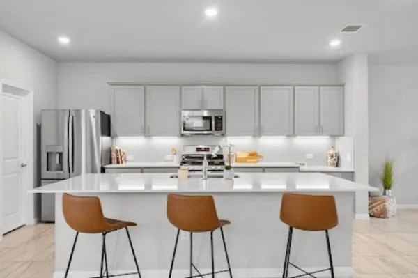a kitchen with stainless steel appliances granite countertop a refrigerator a stove a sink and white cabinets with wooden floor
