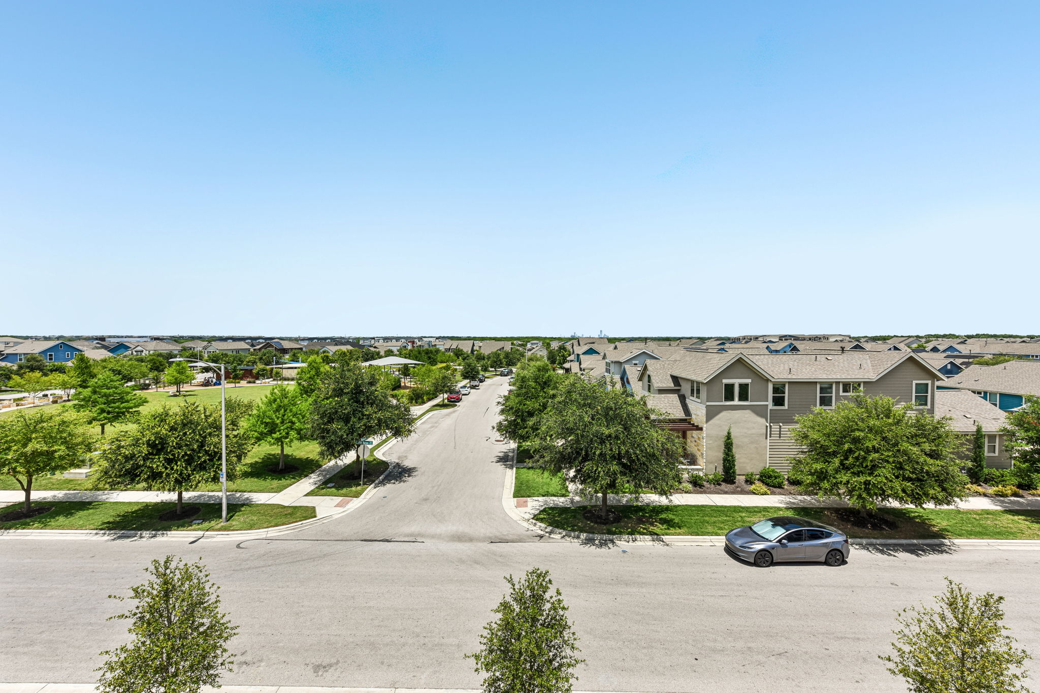 9033 Cattle Baron Path Austin, TX 78747 - Photo 39 of 40 An aerial perspective reveals a serene community with uniform homes and ample green spaces under a clear sky.