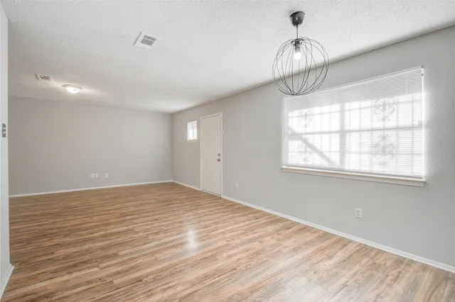 a view of empty room with wooden floor and window