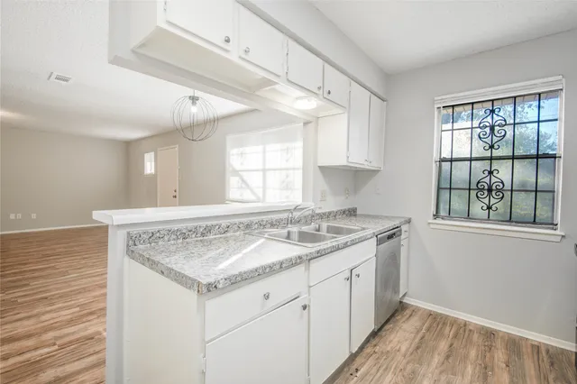 a view of kitchen with granite countertop window sink and cabinets