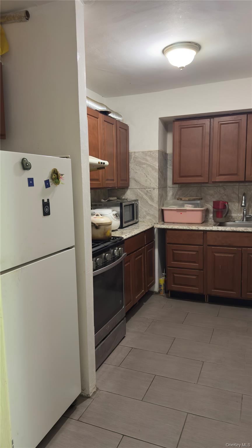58-03 Calloway Street, Unit 4H Queens, NY 11368 - Photo 6 of 10 a kitchen with stainless steel appliances a refrigerator and a sink