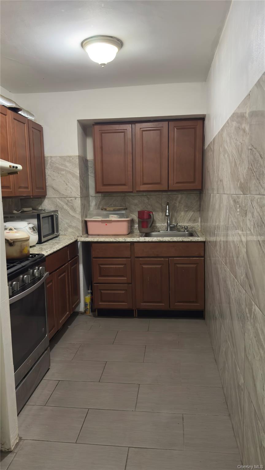 58-03 Calloway Street, Unit 4H Queens, NY 11368 - Photo 7 of 10 a kitchen with stainless steel appliances a sink cabinets and a counter top space