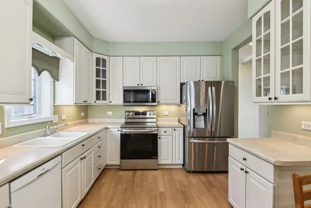 a kitchen with stainless steel appliances a stove a refrigerator island and chairs