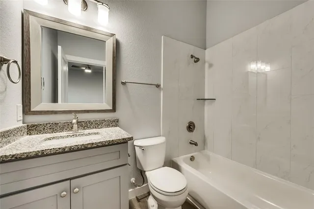 a bathroom with a granite countertop toilet a sink and a bathtub