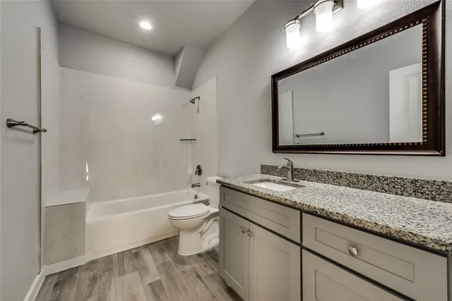 a bathroom with a granite countertop sink a toilet and a bathtub