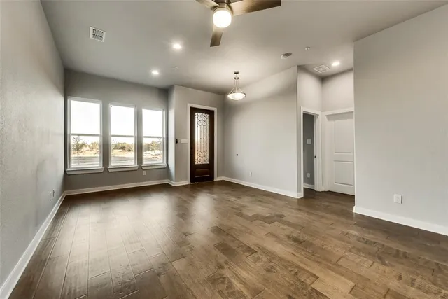 an empty room with windows and ceiling fan
