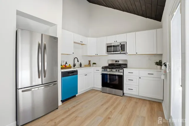 a kitchen with a refrigerator stove and white cabinets