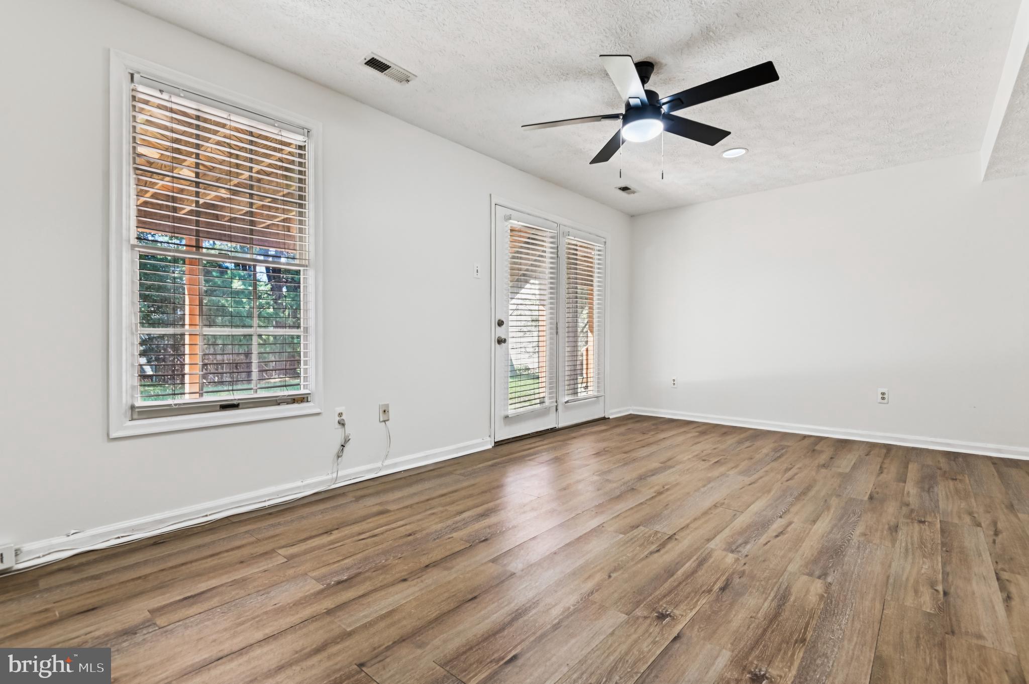 19 Championship Court, Unit K5 Owings Mills, MD 21117 - Photo 27 of 35 an empty room with wooden floor chandelier fan and windows