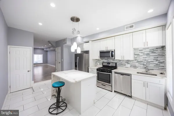 a kitchen with stainless steel appliances kitchen island granite countertop a sink a stove a microwave and cabinets