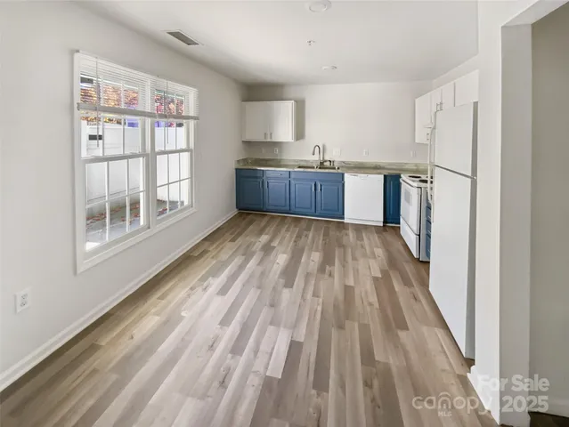 a kitchen with stainless steel appliances granite countertop a refrigerator sink and white cabinets