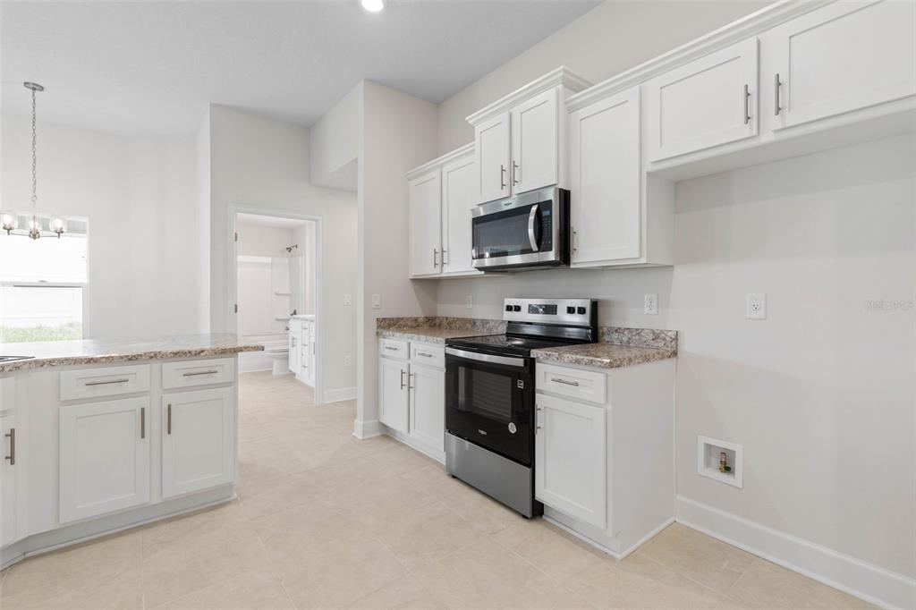 52 Undershire Path Palm Coast, FL 32164 - Photo 17 of 54 a kitchen with granite countertop white cabinets stainless steel appliances and a sink