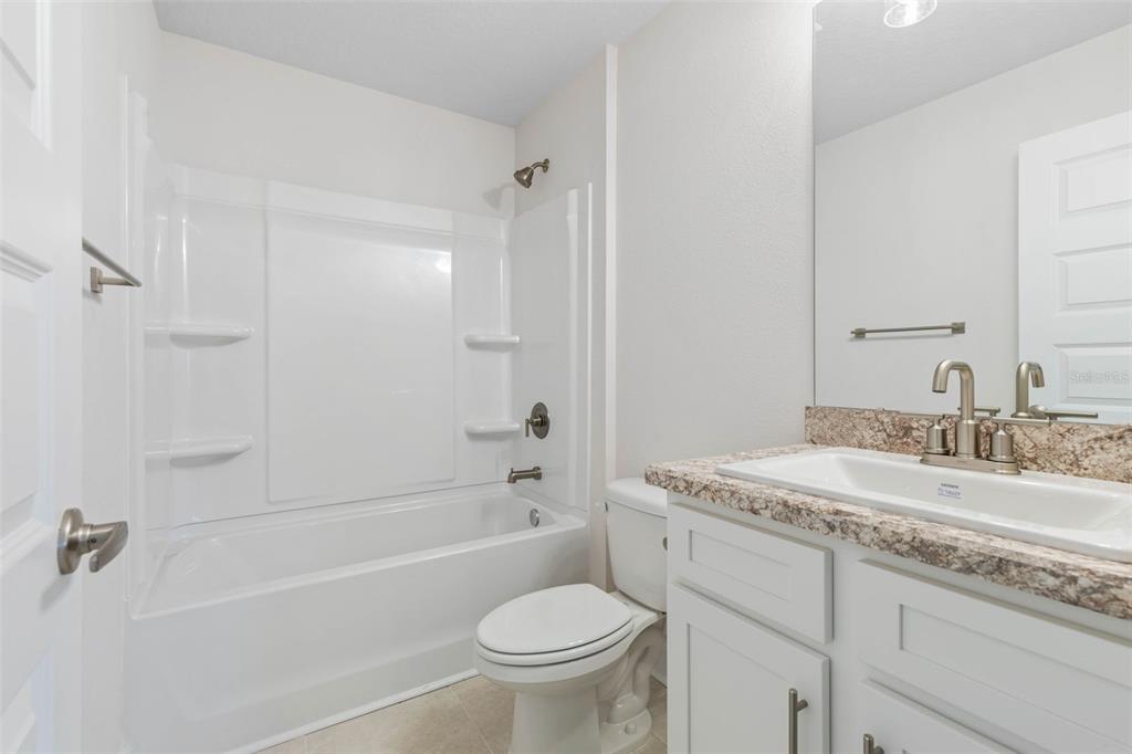 52 Undershire Path Palm Coast, FL 32164 - Photo 28 of 54 a bathroom with a granite countertop toilet a sink and a bathtub