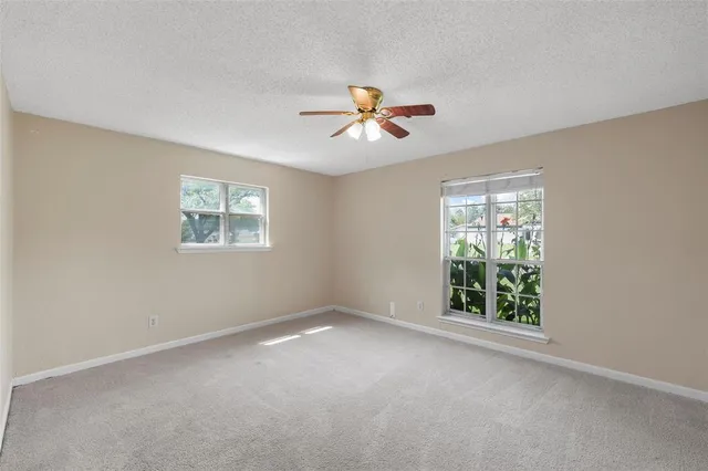 an empty room with windows and chandelier fan