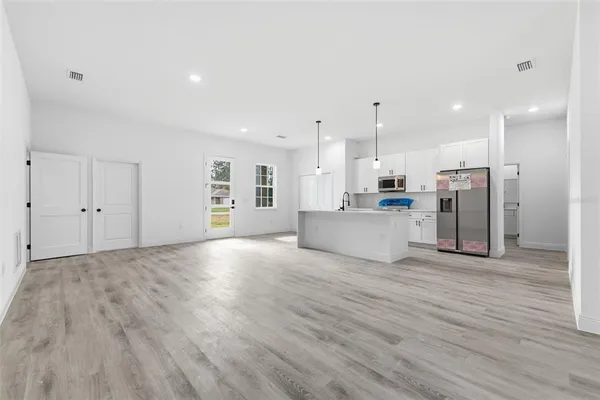 a view of a kitchen with a fridge and wooden floor