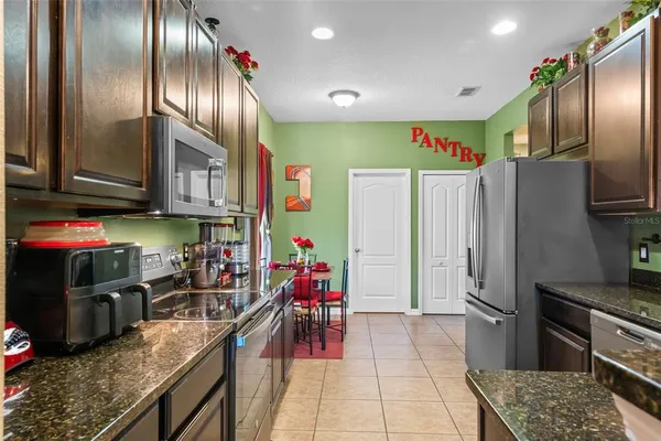 a kitchen with stainless steel appliances granite countertop a refrigerator a stove and a sink