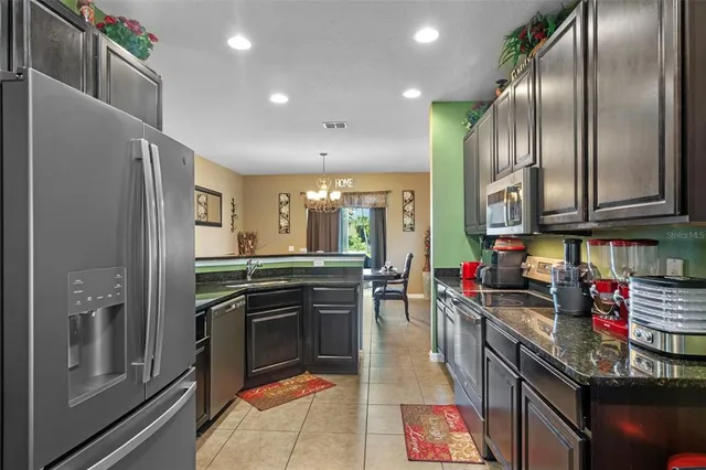 a kitchen with stainless steel appliances granite countertop a refrigerator a stove and a sink