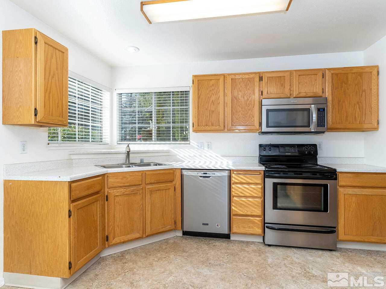 4765 Goodwin Road Sparks, NV 89436 - Photo 11 of 22 a kitchen with stainless steel appliances granite countertop a stove and a microwave