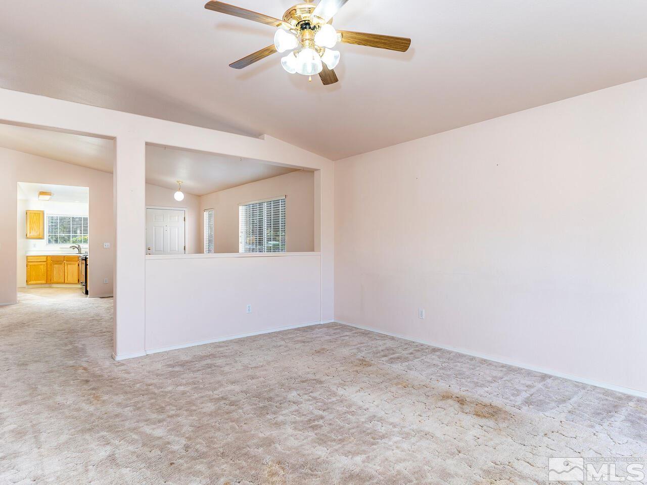 4765 Goodwin Road Sparks, NV 89436 - Photo 8 of 22 an empty room with a chandelier fan and windows