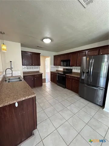 a kitchen with stainless steel appliances granite countertop a refrigerator stove microwave and sink