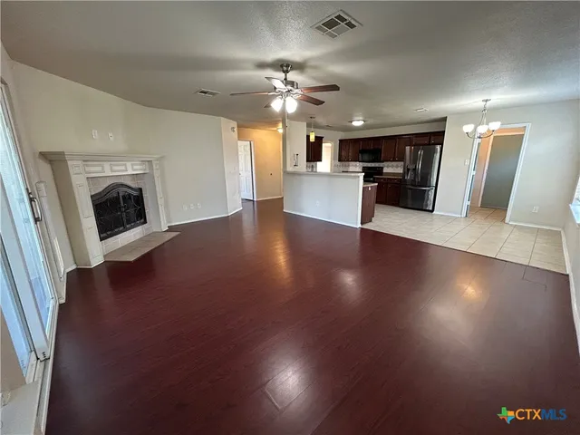 a view of a kitchen with a sink a refrigerator a fireplace and wooden floor