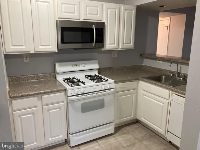a kitchen with white cabinets and white appliances