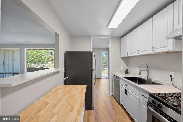 a kitchen with granite countertop white cabinets and stainless steel appliances