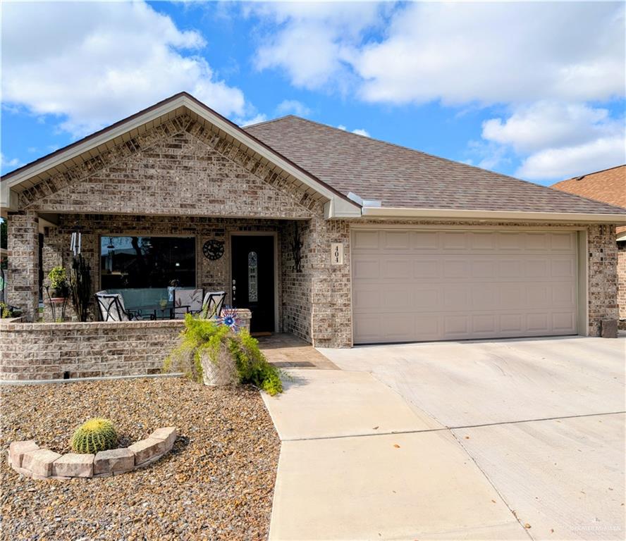 Ranch-style house featuring brick siding, roof with shingles, driveway, and an attached garage