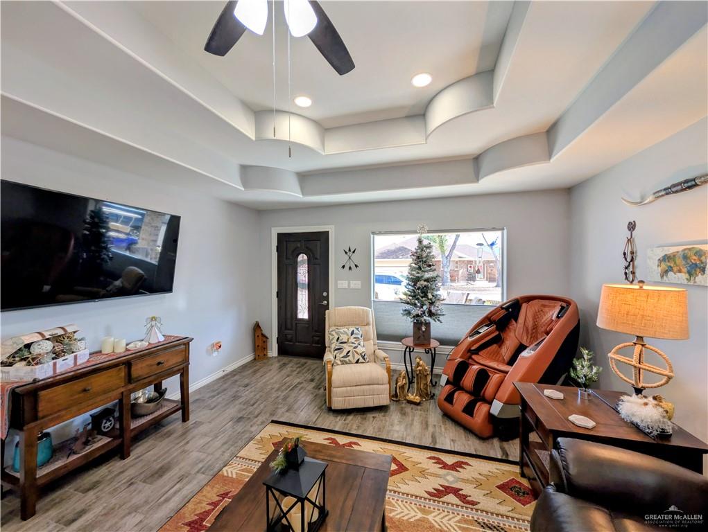 404 Jupiter Street Mission, TX 78572 - Photo 4 of 22 Living area with a raised trey ceiling, wood-style tile floors, ceiling fan, and recessed lighting.