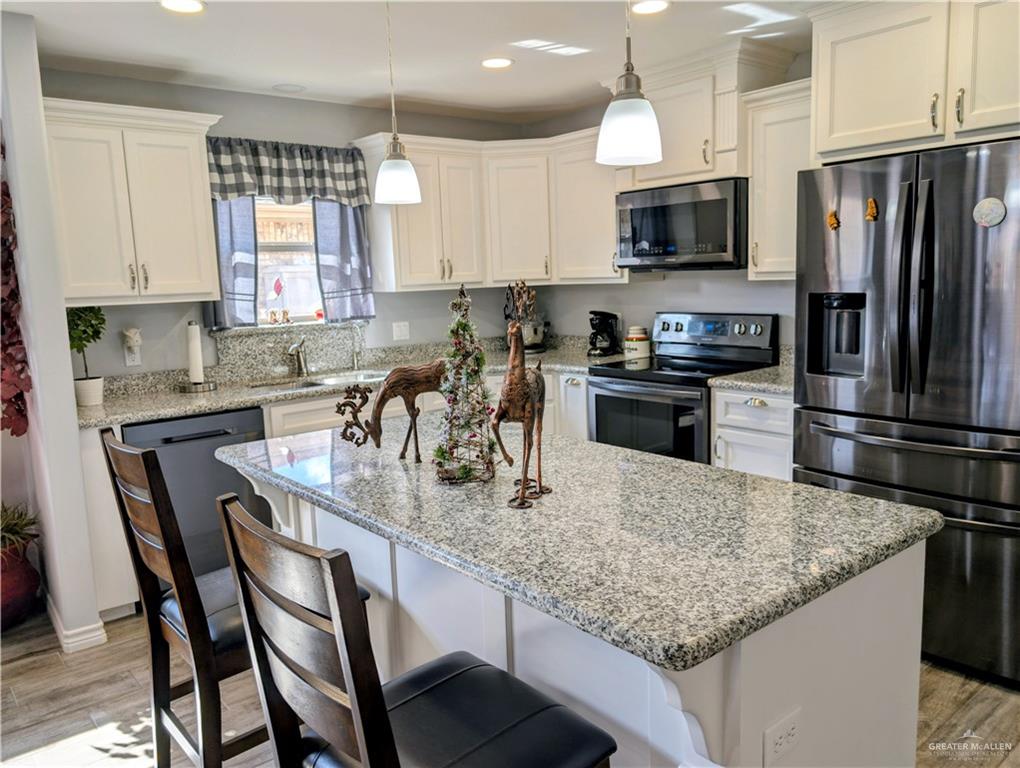 404 Jupiter Street Mission, TX 78572 - Photo 6 of 22 Kitchen with appliances with dark stainless steel finishes, light wood-style floors, hanging light fixtures, a kitchen island, and recessed lighting.